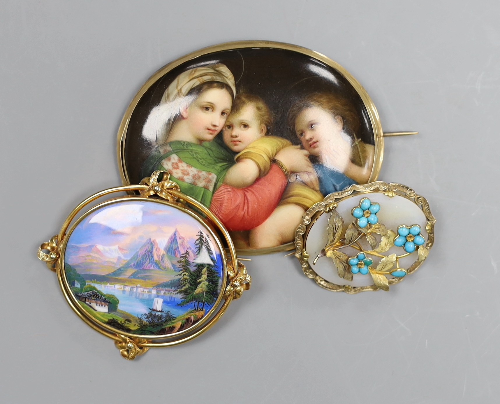 A Victorian 15ct gold mounted porcelain plaque, decorated with the Madonna della Sedia, 8cm, a Swiss landscape enamel brooch with 15ct mount, 6.5cm and a Pinchbeck brooch with turquoise set foliate decoration